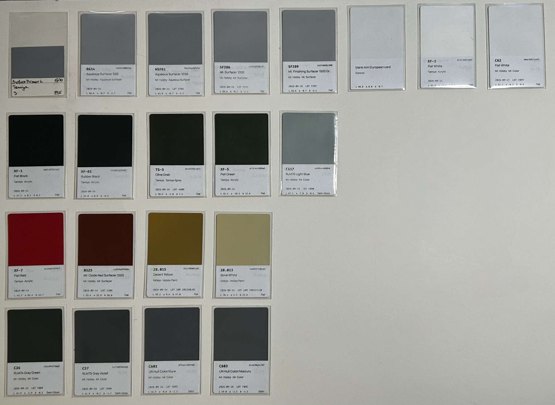 Sprayed mini European cards laid out in 4 rows, each in a sleeve with a printed label giving the paint code, name, range, lot, painting date and measured CIELAB values